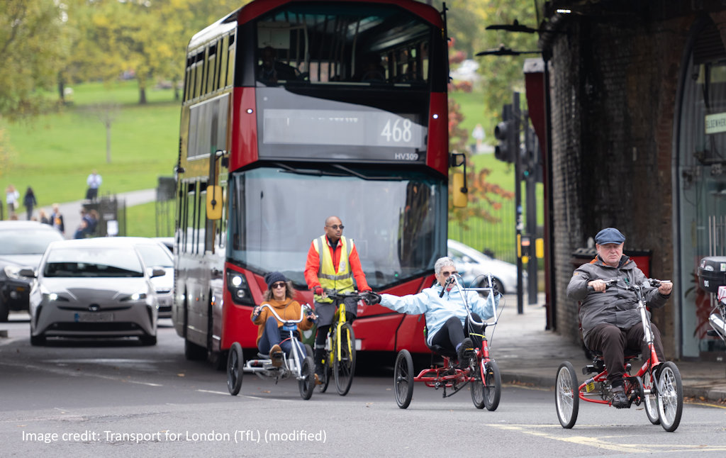 A group of tricycle users cycling in London ahead of a bus.